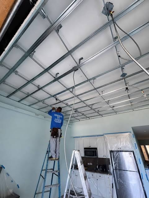 Trabajador instalando estructura metálica de cielo falso en una cocina en remodelación