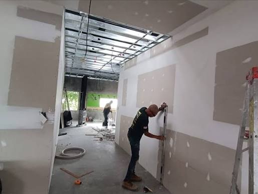 Trabajador instalando placas de drywall en paredes de obra en curso