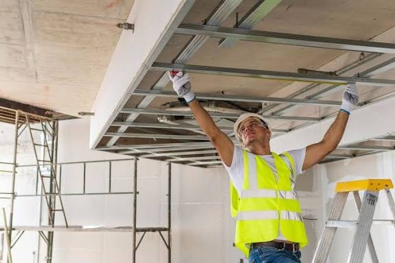 Trabajador con chaleco reflectante instalando estructura metálica de techo